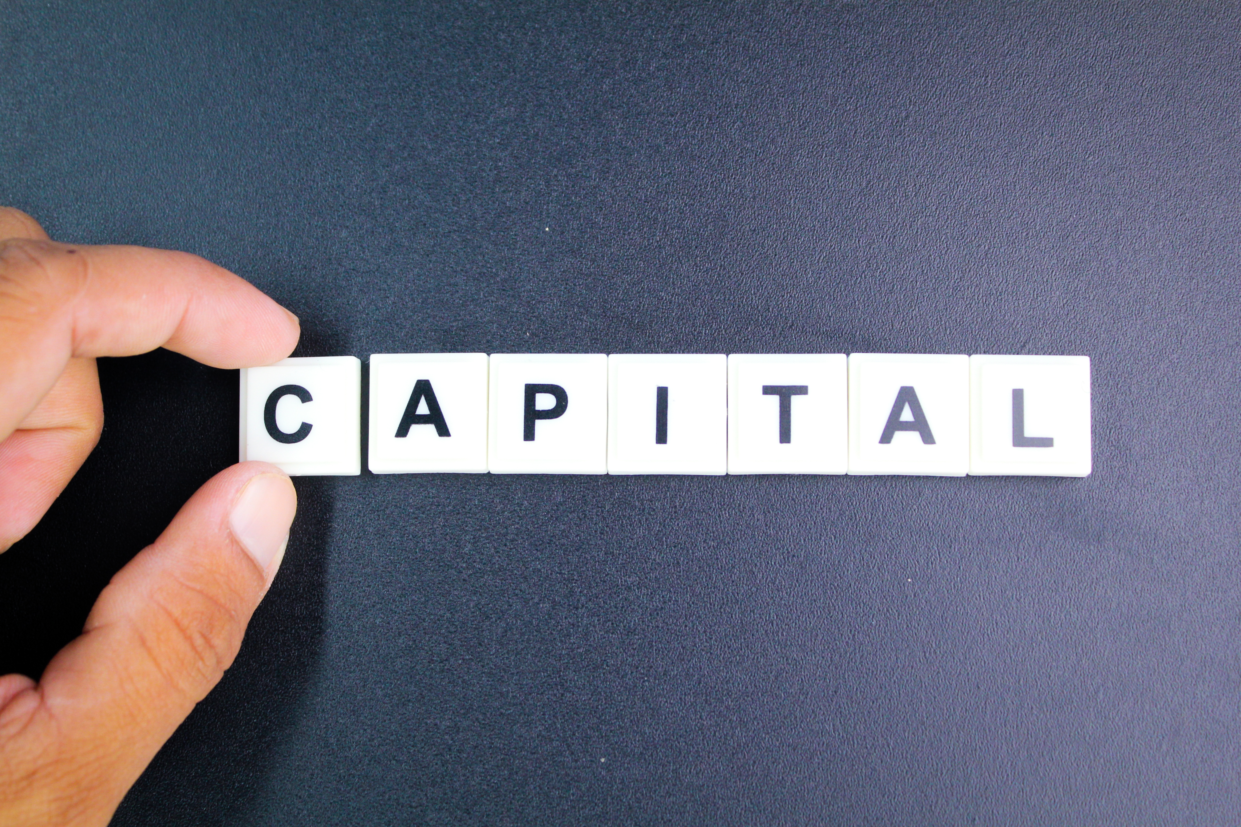 hands holding letters of the alphabet with the word capital.