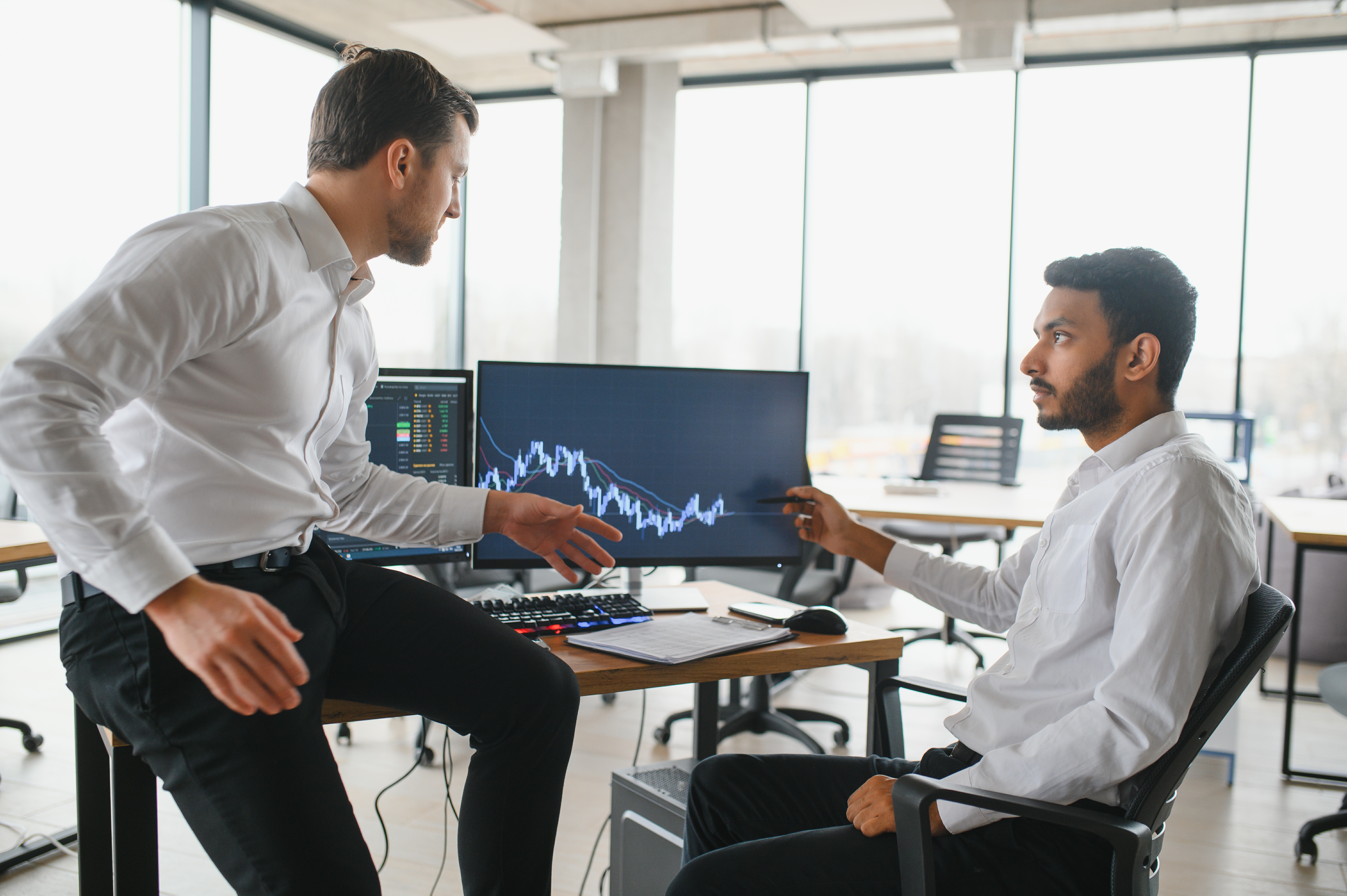 Two trader sitting in office and looking at screen, checking cryptocurrency information data on